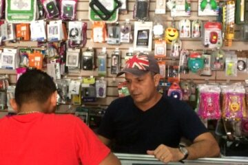 Man behind cell phone counter helping a customer