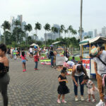 people on a popular trail with tall palm trees and tall city buildings in background